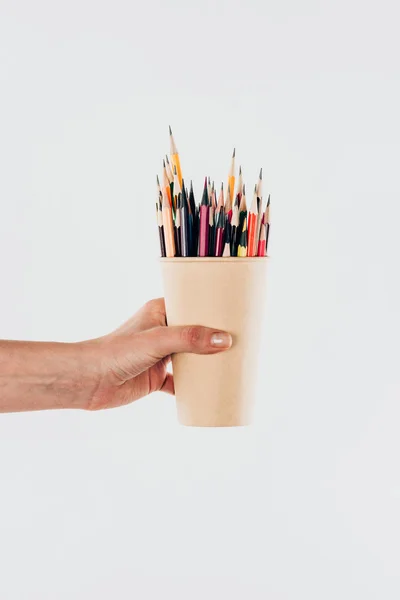 Vista de cerca de la taza de mano femenina con lápices de colores aislados sobre fondo blanco - foto de stock