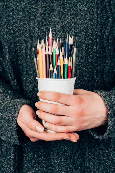 Close-up view of female hands holding cup with colorful pencils — Stock Photo