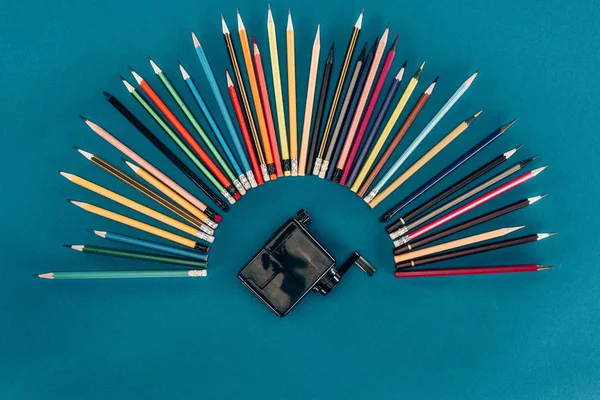 Top view of composition of colorful pencils and sharpener isolated on blue background — Stock Photo