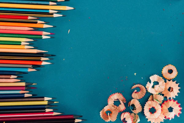 Vue du dessus de la composition des crayons colorés et des découpes isolés sur fond bleu — Photo de stock