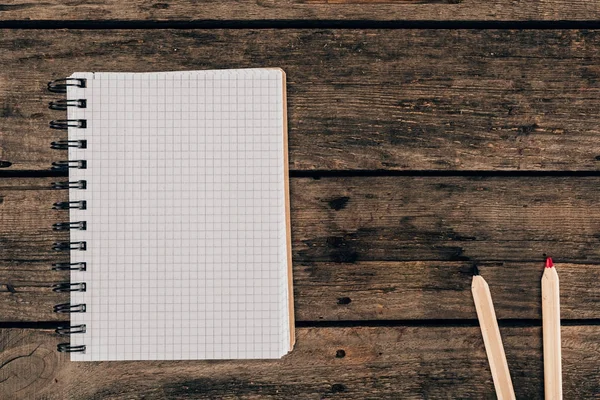 Vista superior de la composición de lápices de colores con cuaderno en blanco sobre fondo de madera - foto de stock