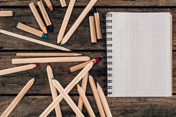 Top view of composition of colorful pencils with blank notebook on wooden background — Stock Photo