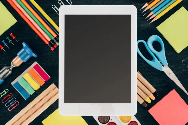 Tableta plana con pantalla en blanco sobre fondo con útiles escolares aislados en la oscuridad — Stock Photo