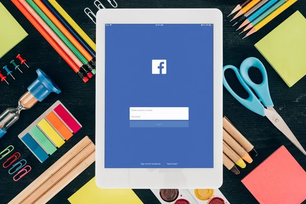 Flat lay tablet con Facebook app su sfondo con materiale scolastico isolato al buio — Foto stock