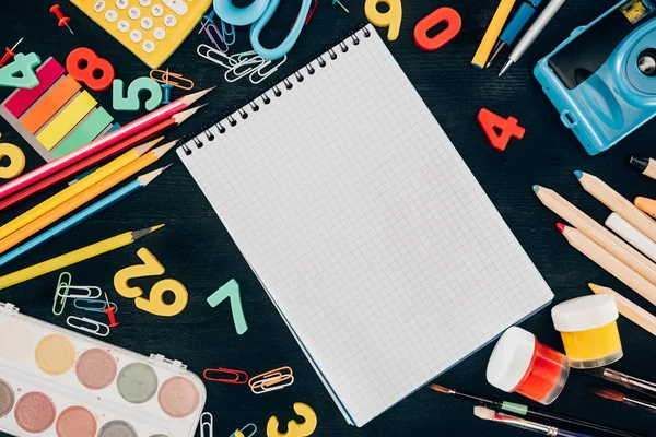 Vue du dessus de la composition de fournitures scolaires colorées avec carnet vierge isolé sur fond de tableau noir — Photo de stock