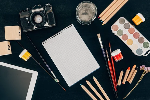 Top view of composition of colorful school supplies with blank notebook isolated on dark board background — Stock Photo