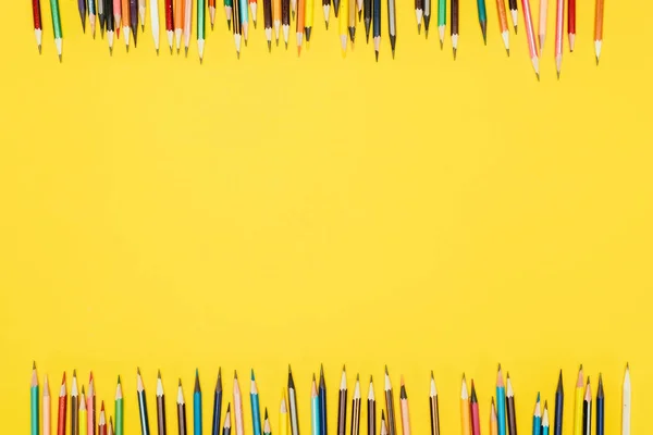 Верхний вид рамки разноцветных карандашей, выделенных на желтом фоне — стоковое фото