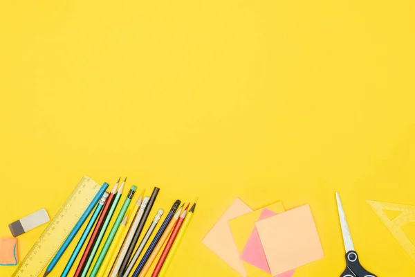 Vue du dessus de la composition des fournitures scolaires colorées isolées sur fond jaune — Photo de stock