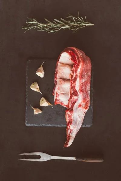 Vue de dessus des côtes de porc crues tranche et ail sur ardoise de pierre — Photo de stock