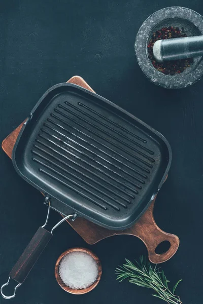 Вид сверху на пустую сковороду-гриль со специями на черном столе — стоковое фото