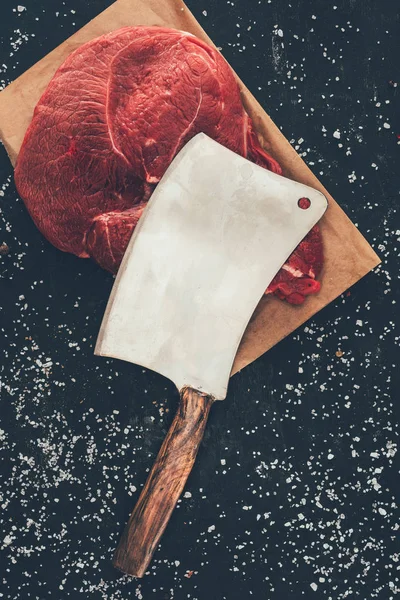 Vista dall'alto di bistecca cruda con mannaia da macellaio su tavola di legno — Foto stock