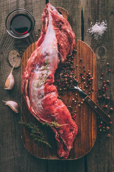 Vue du dessus de la viande de porc crue avec des épices sur planche à découper en bois — Photo de stock