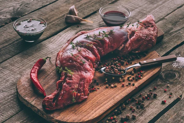 Close-up shot of raw pork meat with spices on wooden cutting board — Stock Photo