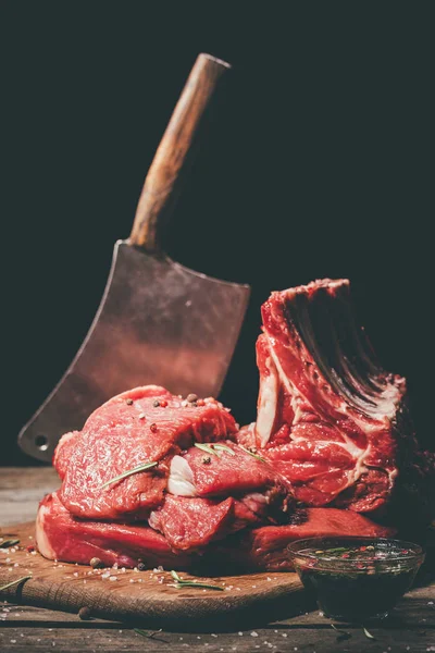 Varios carne cruda y cuchilla en tabla de cortar de madera - foto de stock