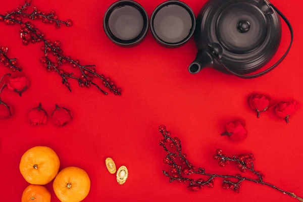 Vue du dessus de la composition du nouvel an chinois avec du thé et des branches de baies sur rouge — Photo de stock