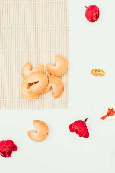 Vue de dessus des biscuits chinois de fortune et des fleurs isolées sur le blanc, concept de Nouvel An chinois — Photo de stock