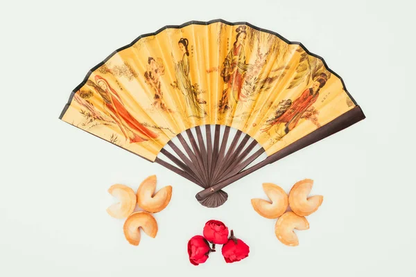 Top view of traditional chinese handheld fan with flowers and fortune cookies isolated on white — Stock Photo