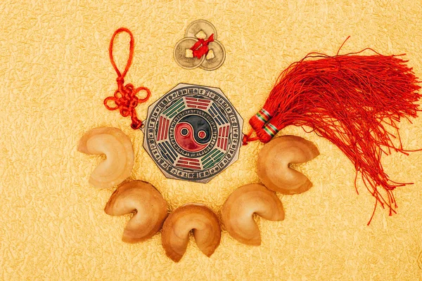 Vista superior del talismán chino rodeado de galletas de la fortuna en la superficie dorada, concepto de año nuevo chino - foto de stock