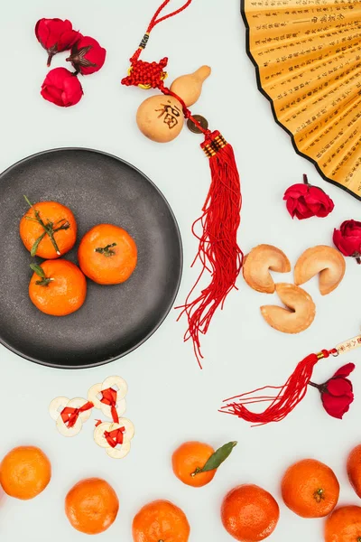 Vista superior de biscoitos da sorte chineses com tangerinas e talismãs tradicionais isolados no conceito branco, Ano Novo Chinês — Fotografia de Stock
