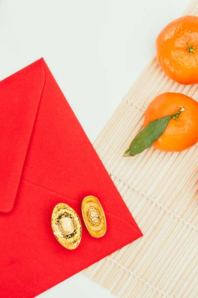 Top view of red envelope with tangerines and chinese golden ingots, Chinese New Year concept — Stock Photo