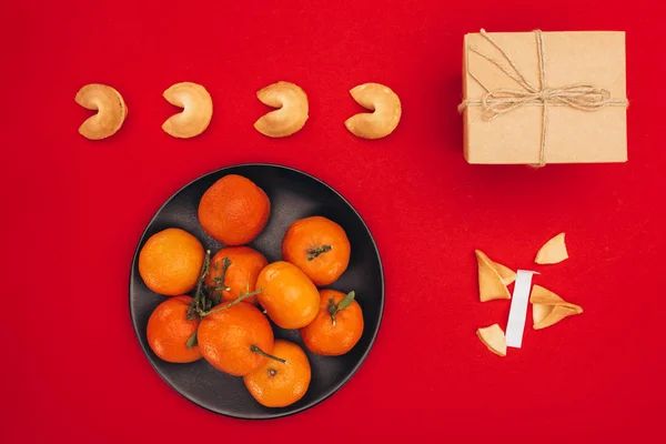 Vista superior de biscoitos da sorte chineses e tangerinas na superfície vermelha como a composição do ano novo chinês — Fotografia de Stock