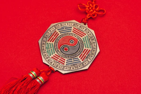 Primer plano del yin chino y el talismán yang en la superficie roja - foto de stock