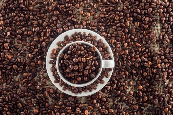 Vista dall'alto di tazza di caffè e chicchi di caffè tostati su vestiti sacco — Foto stock