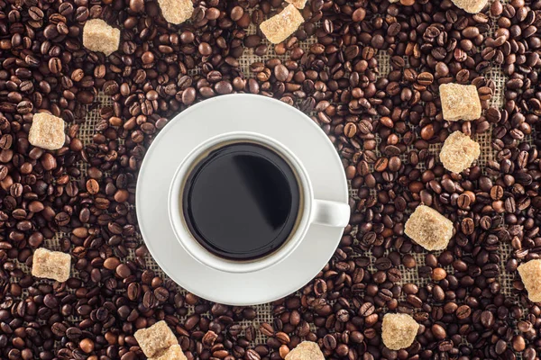 Top view of cup of coffee, brown sugar, coffee beans on sack clothes — Stock Photo