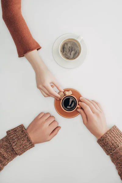 Верхний вид человеческих рук и чашки кофе с сахаром на белом — стоковое фото
