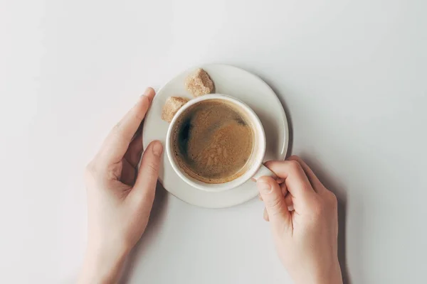 Vista superior de las manos humanas y taza de café con azúcar en blanco - foto de stock
