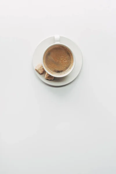 Vue du dessus de tasse de café aromatique avec soucoupe et sucre brun isolé sur blanc — Photo de stock