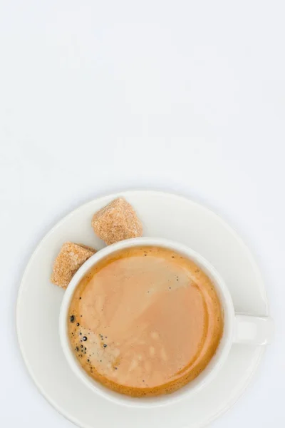 Vue du dessus de tasse de café avec soucoupe et sucre brun isolé sur blanc — Photo de stock