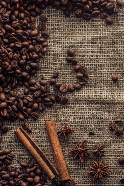 Roasted coffee beans with cinnamon sticks and star anise on sackcloth — Stock Photo