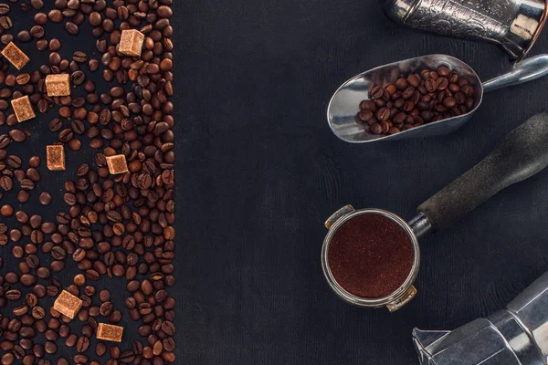 Vista superior de grãos de café torrados, açúcar, colher, adulteração de café, cafeteira e cafeteira em preto — Fotografia de Stock