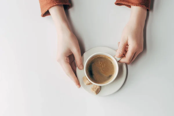 Vista recortada de las manos humanas y taza de café en gris - foto de stock