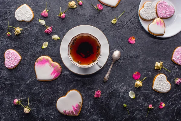 St valentines day flat lay with cup of tea, glazed heart shaped cookies and decorative flowers on dark tabletop — Stock Photo