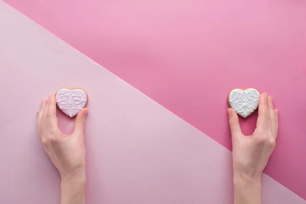 Vue partielle de la femme tenant des biscuits glacés dans les mains sur rose, st concept Saint-Valentin — Photo de stock