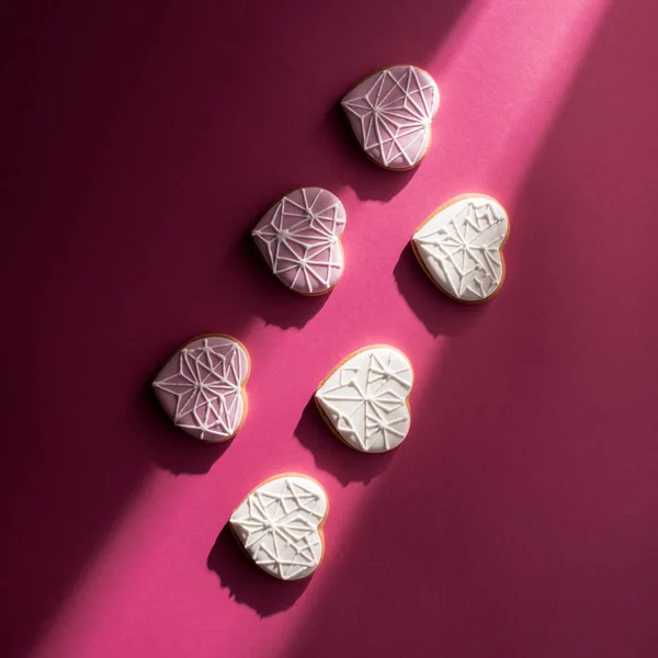 Vista superior de las galletas vidriadas en forma de corazón en la mesa rosa - foto de stock