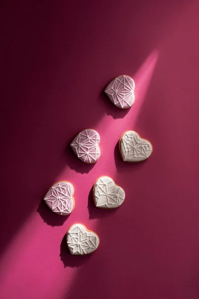 Vista superior de las galletas vidriadas en forma de corazón en la mesa rosa - foto de stock