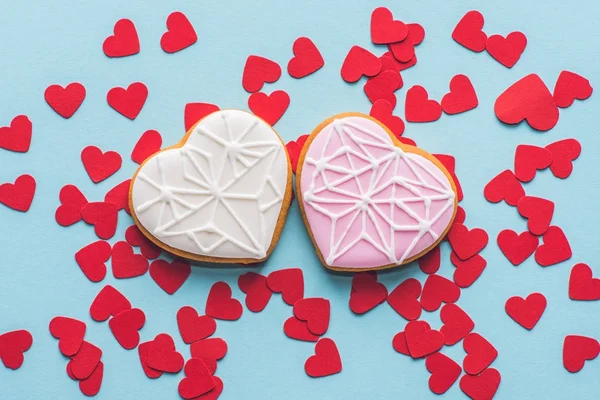 Vista superior de galletas en forma de corazón y confeti decorativo rojo aislado en azul - foto de stock