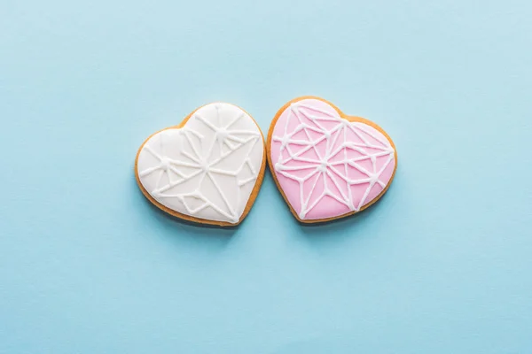 Draufsicht auf zwei glasierte herzförmige Kekse isoliert auf blauem, st Valentinstag Urlaubskonzept — Stockfoto