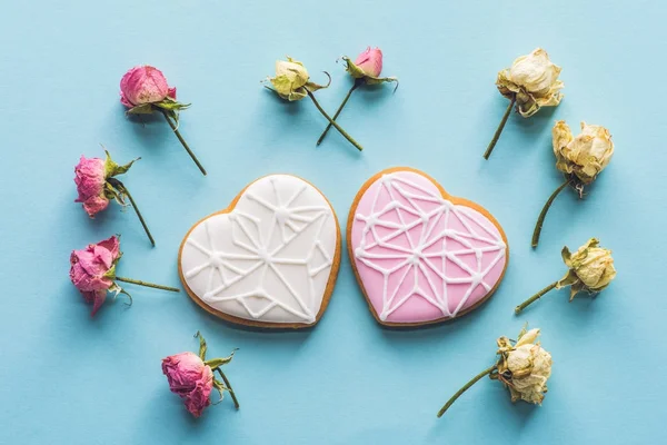 Vista superior de cookies em forma de coração e flores decorativas isoladas em azul — Fotografia de Stock