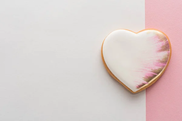Vista dall'alto del biscotto a forma di cuore smaltato sulla superficie rosa — Foto stock