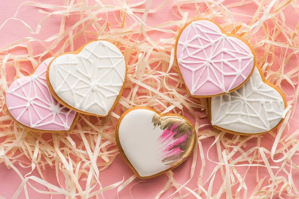 Vue rapprochée de biscuits doux en forme de coeur et de paille décorative sur rose, concept de vacances St Valentin — Photo de stock