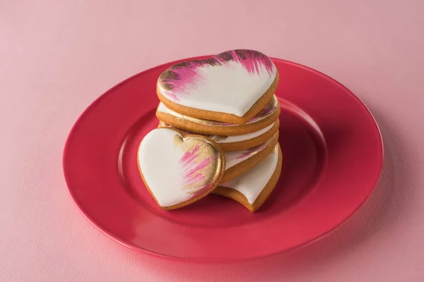 Vue rapprochée des biscuits vitrés en forme de coeur sur plaque isolée sur rose — Photo de stock