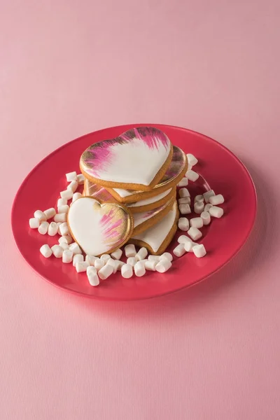 Vista de cerca de las galletas en forma de corazón y malvavisco en la placa aislada en rosa - foto de stock