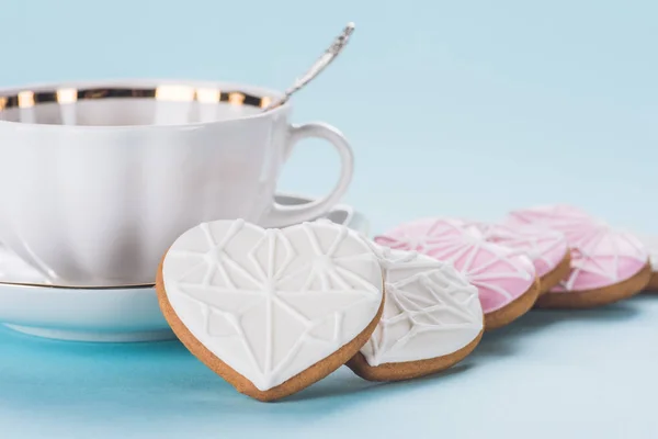 Vue rapprochée des biscuits en forme de coeur et tasse isolée sur bleu — Photo de stock
