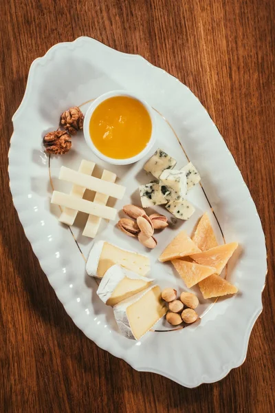 Vista dall'alto del piatto di formaggio con noci e salsa sul tavolo di legno — Foto stock