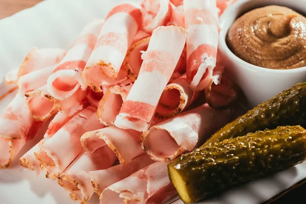 Vista de cerca del tocino en rodajas servido con salsa y pepinos en escabeche en el plato - foto de stock