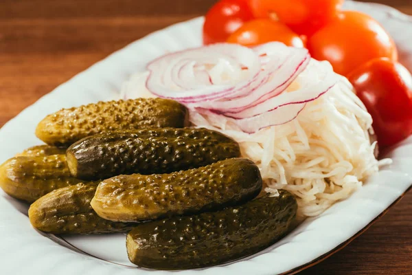 Close-up view of sauerkraut served with pickled vegetables on white plate — Stock Photo